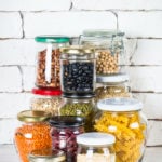 Cereals, Legumes, and beans in glass jars on white kitchen table. Rice, corn, quinoa, beans, soy, lentils, mache, pasta. Healthy food for cooking.
