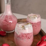 two glasses and a bottle of rose falooda in a tray with a tray