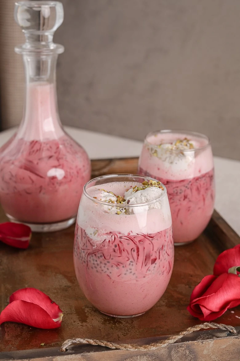 two glasses and a bottle of rose falooda in a tray with a tray