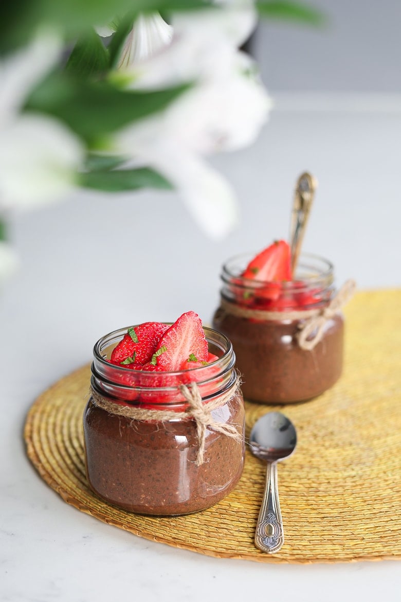 two small jars of chocolate chia pudding topped with fresh strawberries