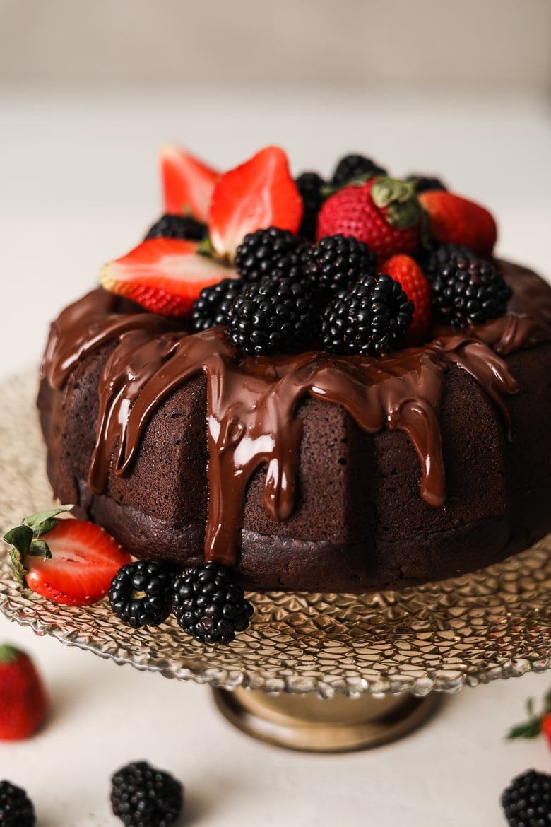 vegan chocolate cake bundt style on a stand topped with berries