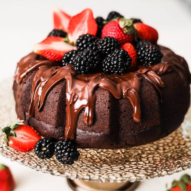 vegan chocolate cake bundt style on a stand topped with berries