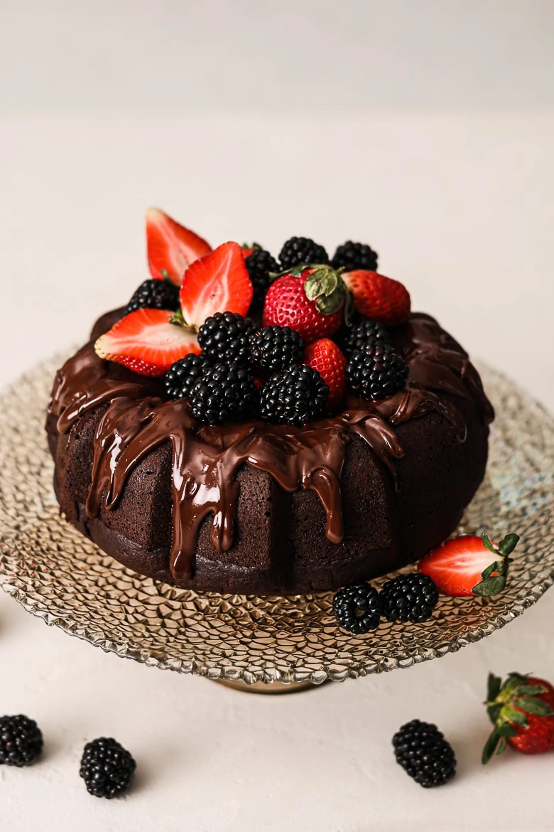 vegan chocolate cake bundt style on a stand topped with berries