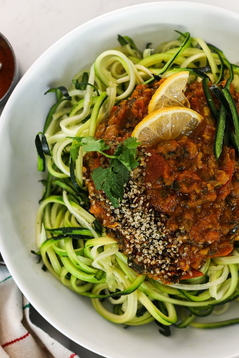 a bowl of zucchini noodles spaghetti topped with a simple curry sauce with lemon slices