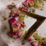 Persian love cake slice topped with icing and dried roses and crushed pistachios