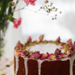 Persian love cake topped with icing and dried roses and crushed pistachios