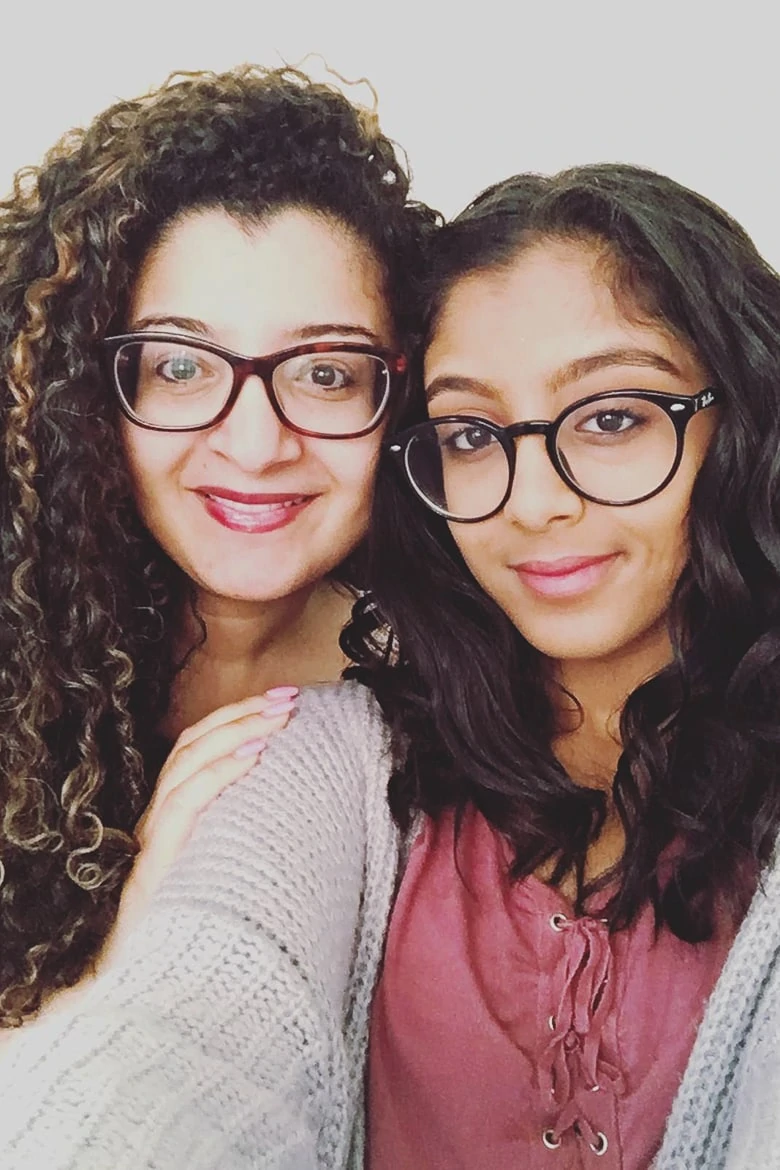 two ladies posing for the camera - one with straight hair and the other with curly hair