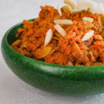 close up of green bowl with carrot halwa aka gajjar halwa - topped with nuts