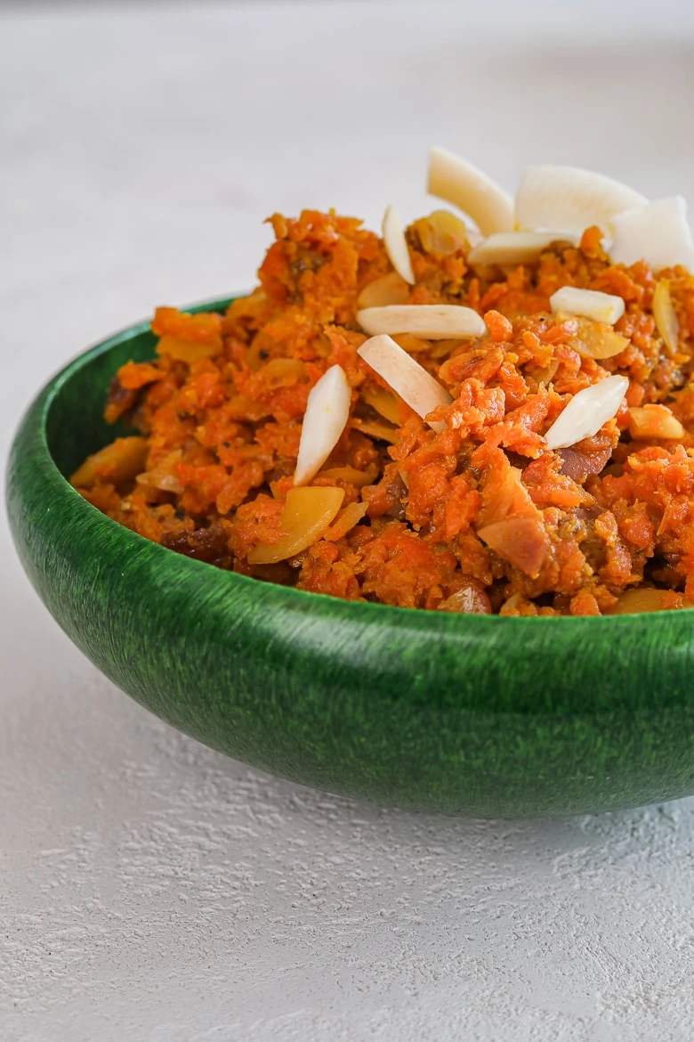 close up of green bowl with carrot halwa aka gajjar halwa - topped with nuts
