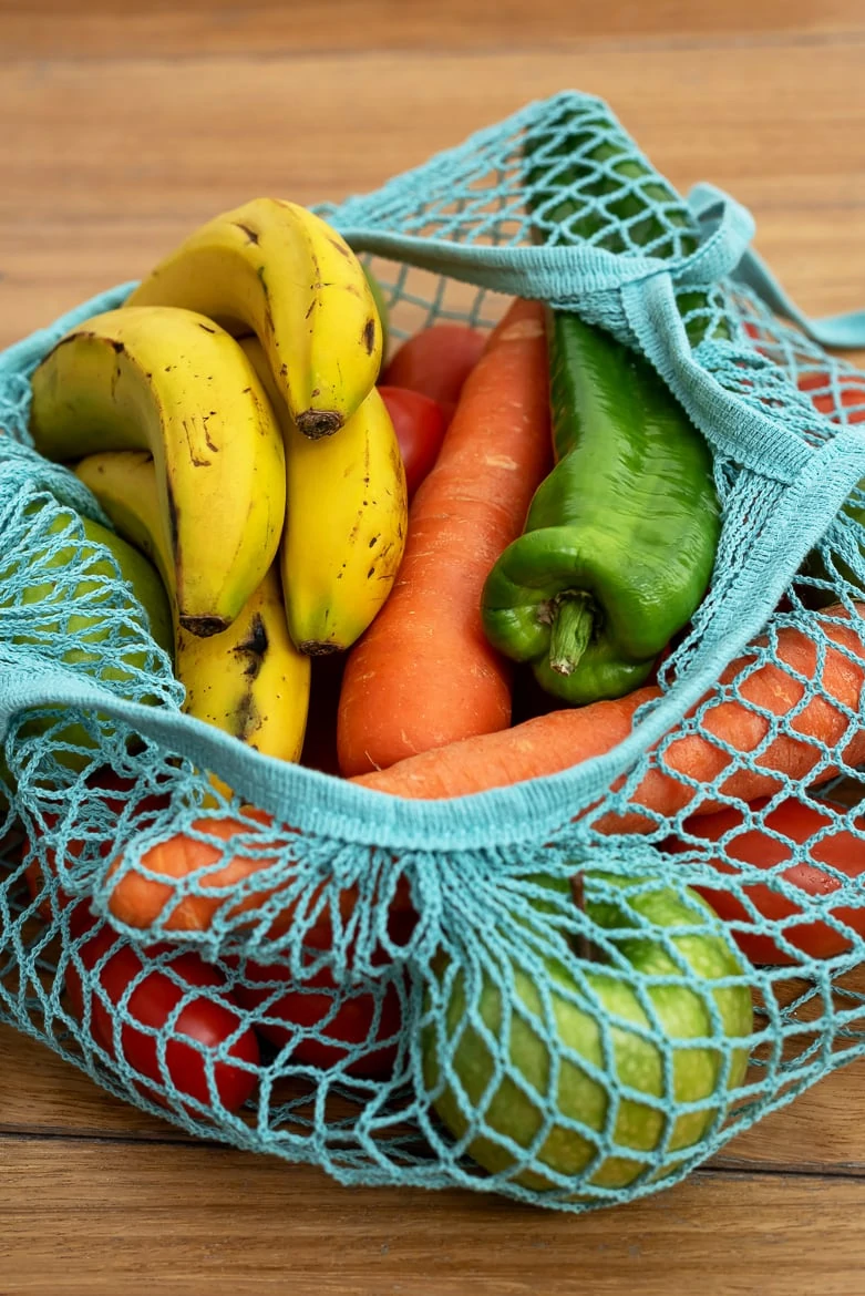 Cotton string eco bag with fruits and vegetables on wooden background