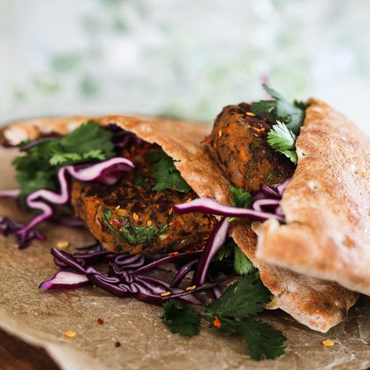 two pita breads stuffed with vegan kebab, purple cabbage and cilantro leaves