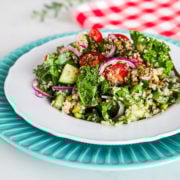 a plate of kale and quinoa salad with tomatoes, red onion and mung beans