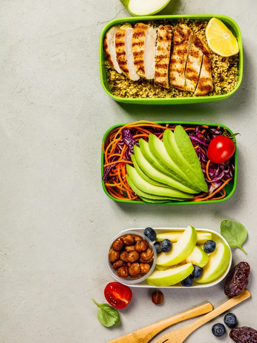 Healthy meal prep containers: Couscous with grilled chicken breast, salad, avocado, berry, apple, and dry dates. Healthy food concept. Top view