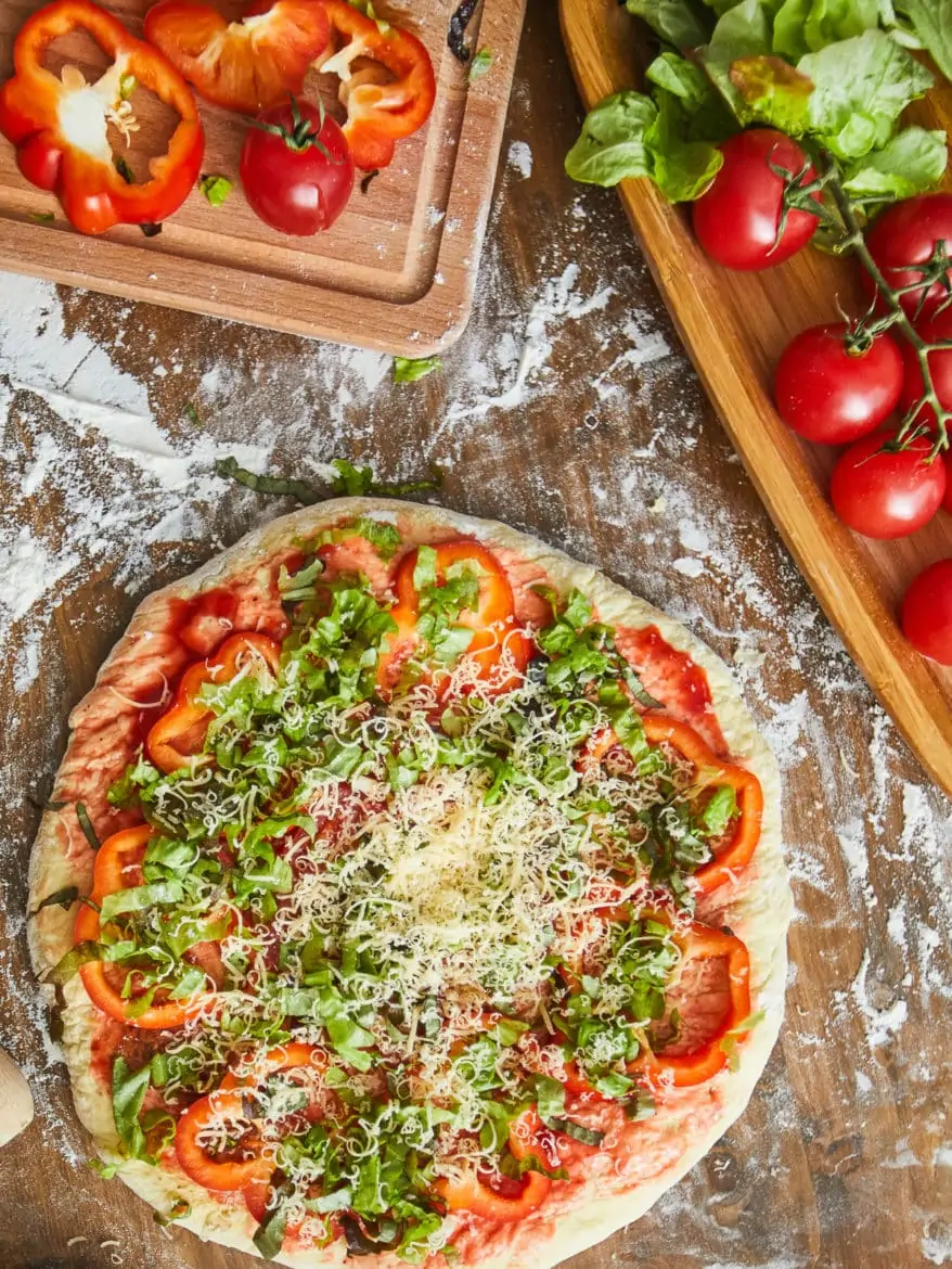 High angle view of homemade pizza with vegetables and cheese on wooden table