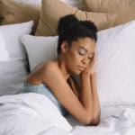 attractive african american girl sleeping on pillows in bed
