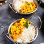 Vegetarian curry with cauliflower and chickpeas served in metal bowls with rice, healthy vegan food, indian cuisine