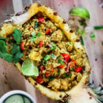 half a pineapple stuffed with Thai pineapple fried rice topped with a lime segment and cilantro.