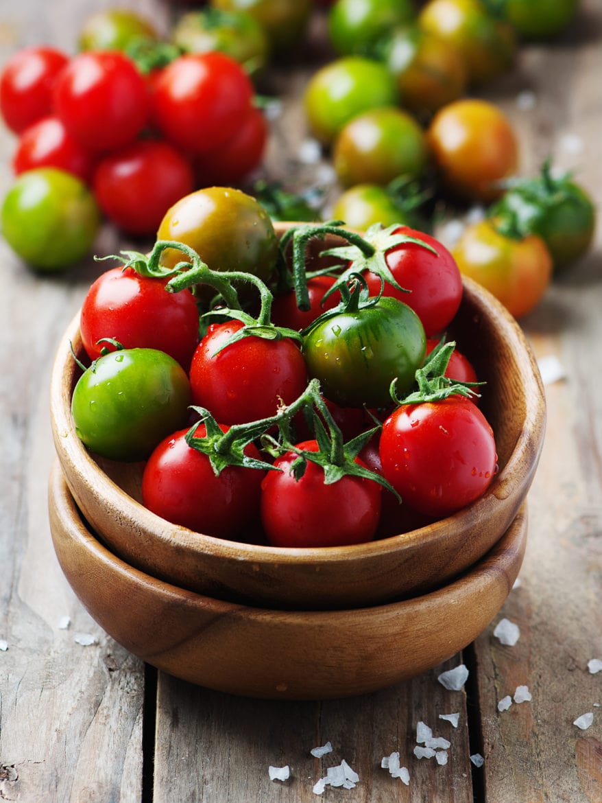 Concept of vegan food, selective focus colourful tomatoes in a wooden bowl