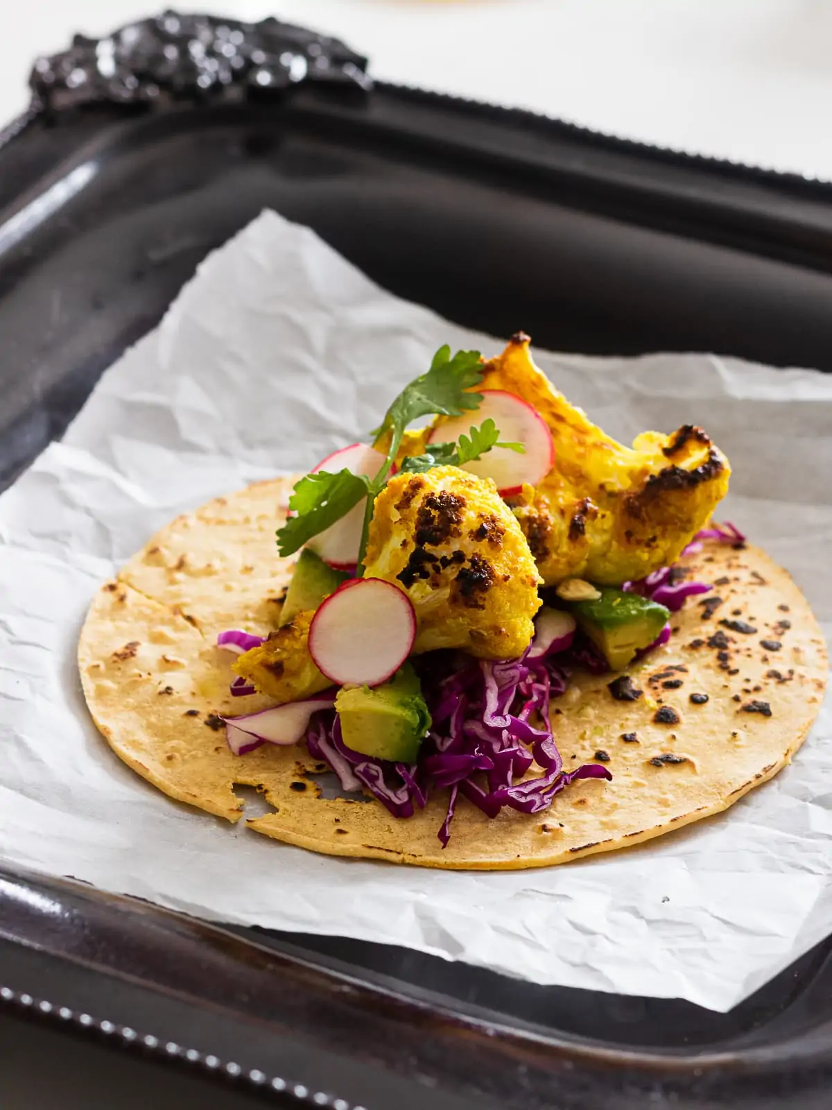 tandoori cauliflower florets on a corn tortilla with red cabbage and herbs