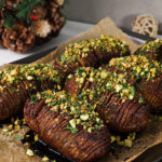 overhead view of baked hasselback potatoes topped with a nut-herb crumble - 6 potatoes on a baking sheet.