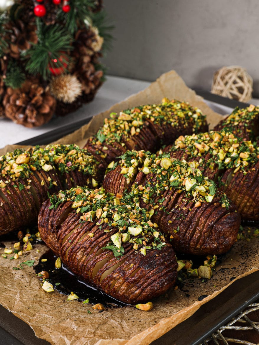 overhead view of baked hasselback potatoes topped with a nut-herb crumble - 6 potatoes on a baking sheet.