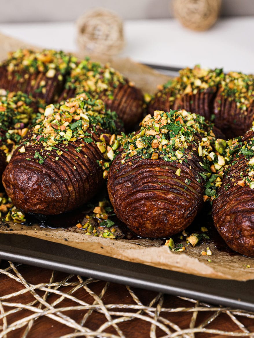 side angle of baked hasselback potatoes topped with a nut-herb crumble