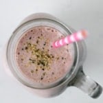 birds eye view of homemade protein shake topped with hemp hearts and pink in colour, with a pink straw inside the jar.