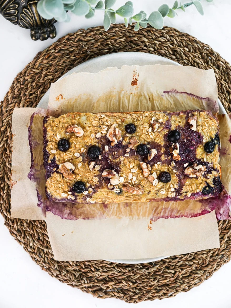 flatlay shot of baked oatmeal squares (uncut) topped with blueberries and walnuts.