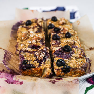 Plate of baked oatmeal squares cut into 6 pieces topped with blueberries