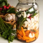 a jar filled with water and chopped mixed vegetables.