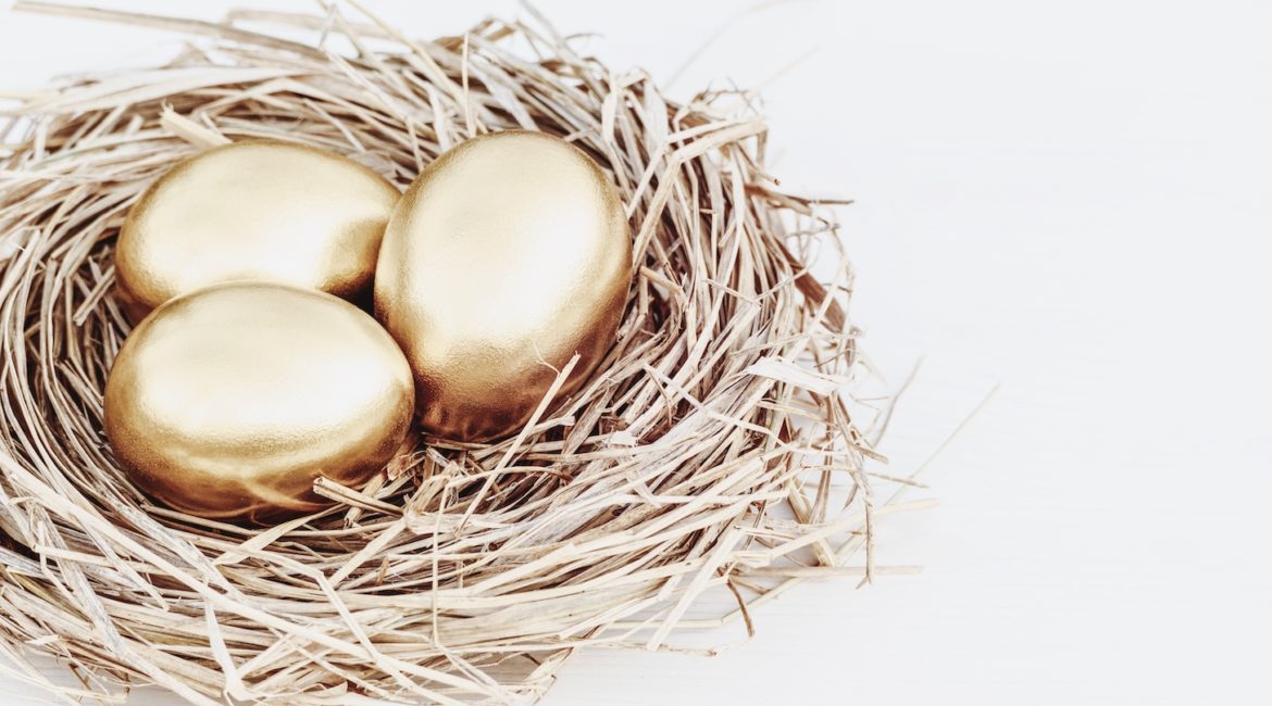 Gold colored eggs in straw nest on white table
