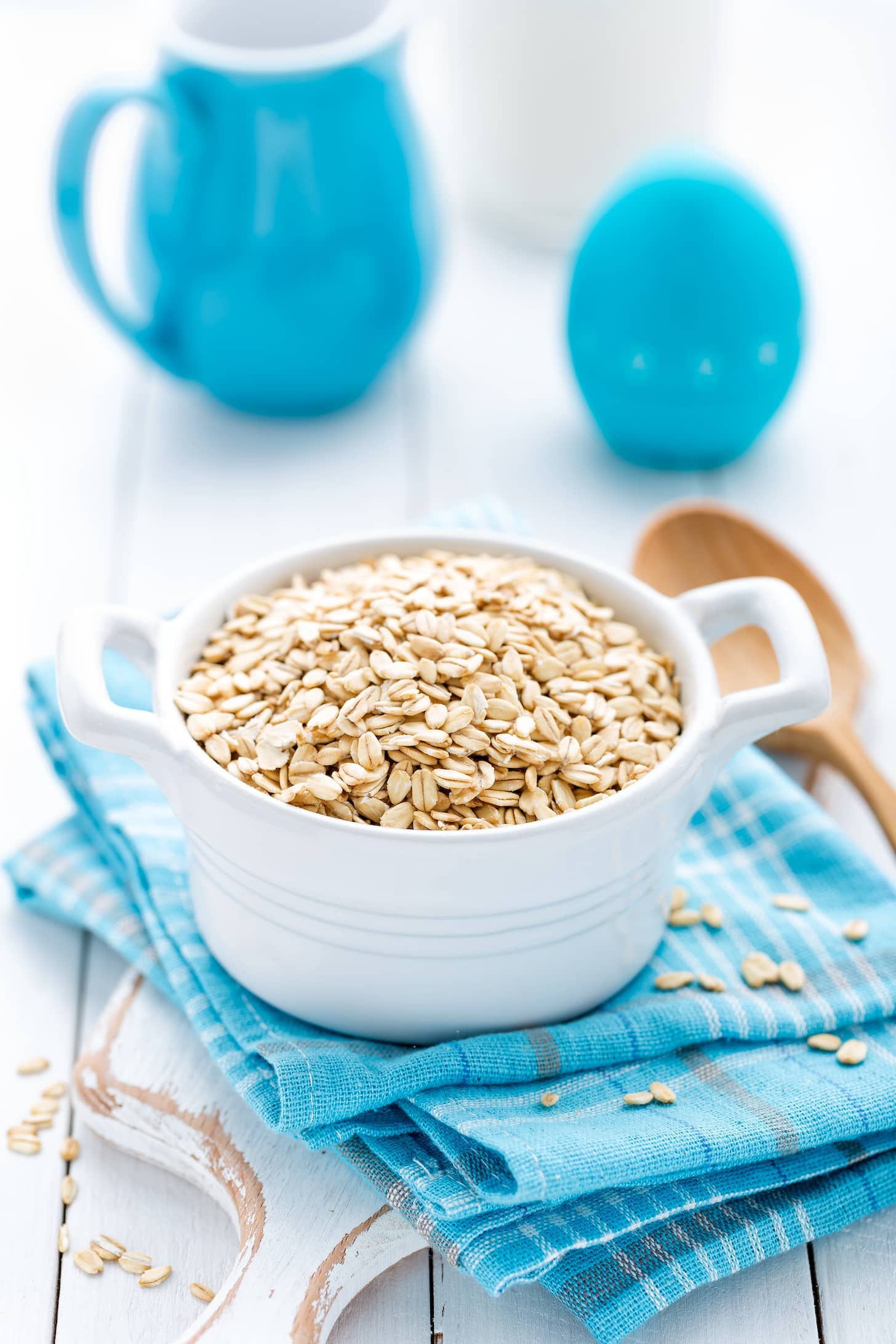 Rolled oats on white wooden background.
