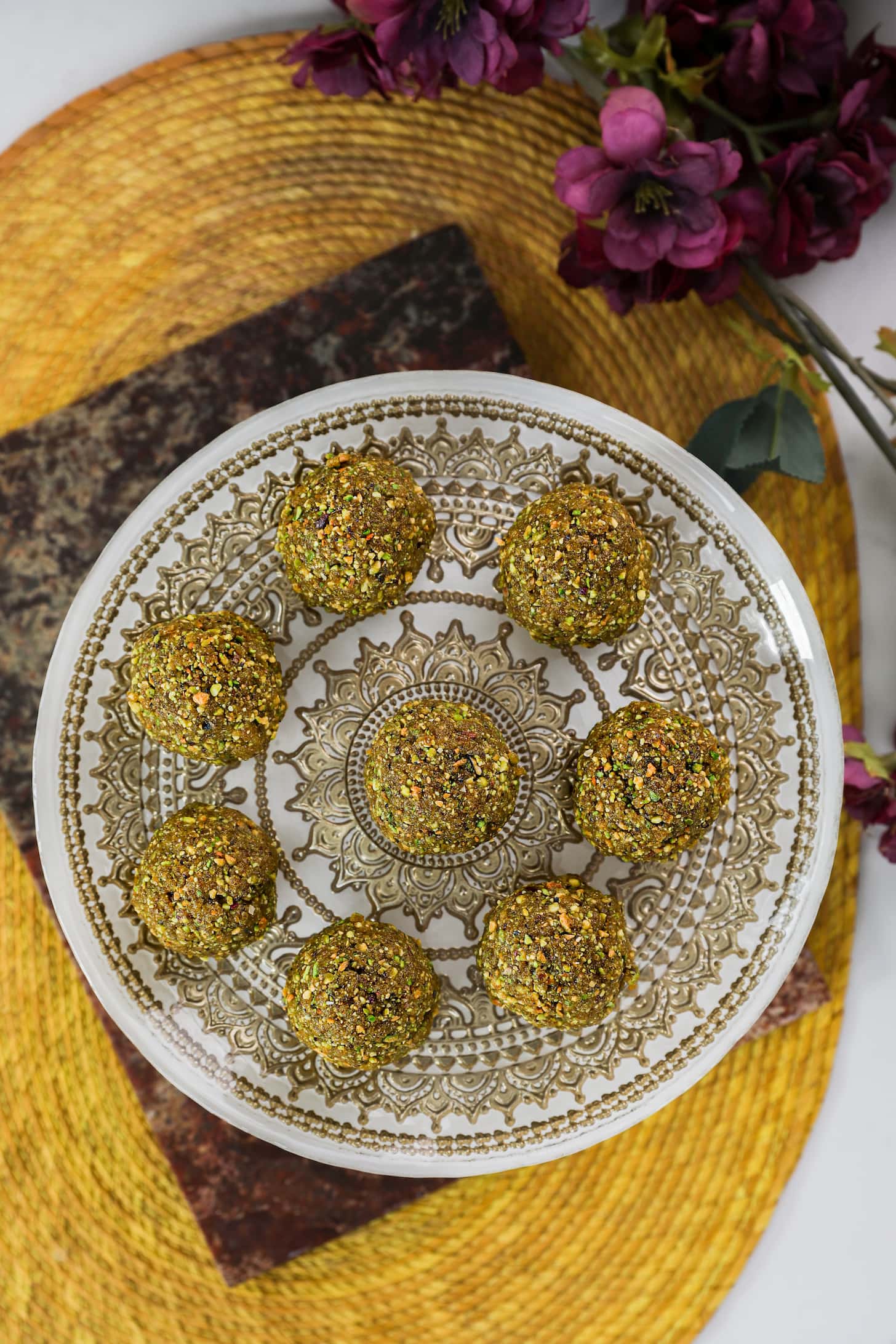 a gold printed plate holding eight brown balls with flowers on one side.