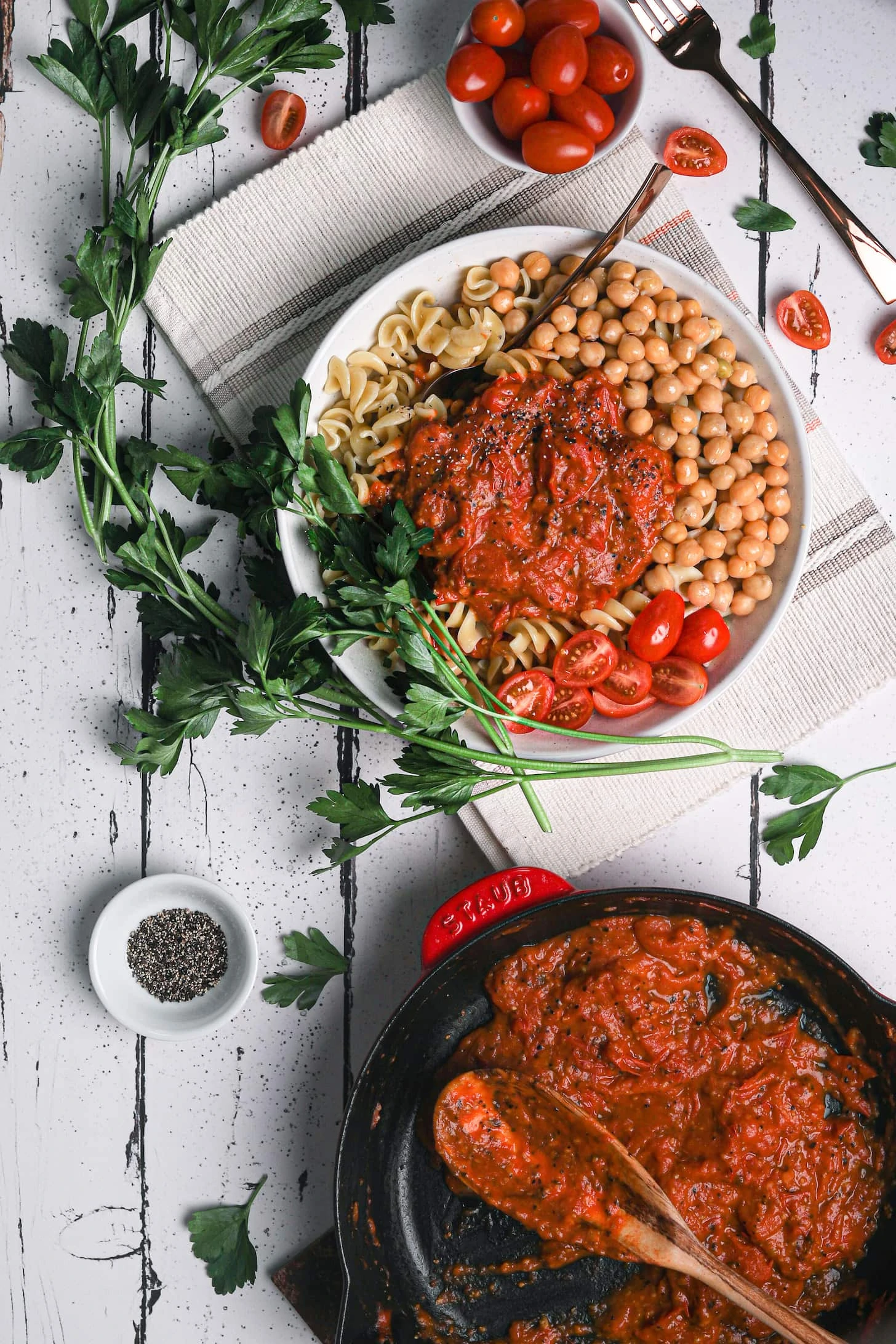 flatlay shot of bowl of pasta with chickpeas topped with sauce.