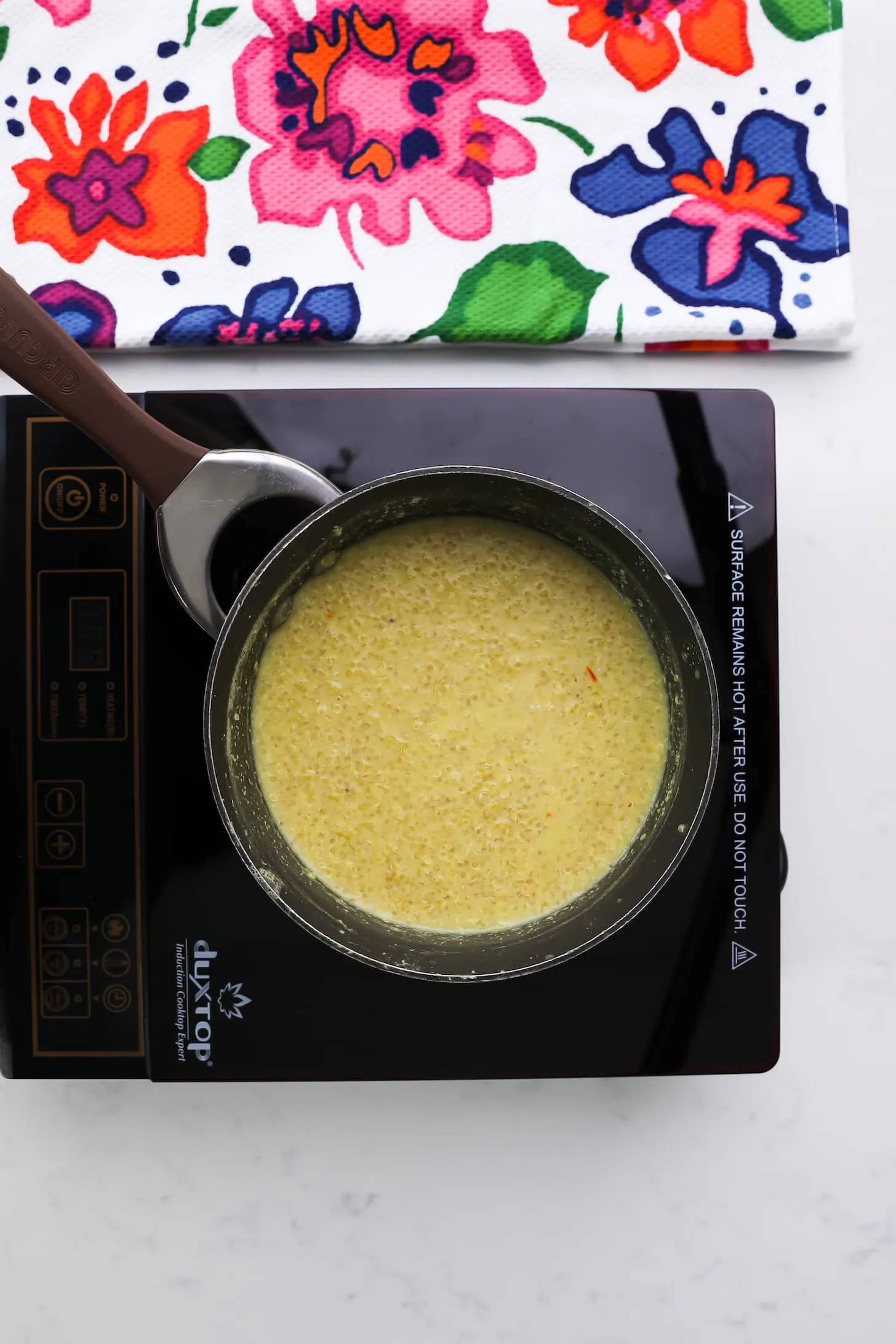 a saucepan with of yellow grainy sauce on a mobile stovetop.