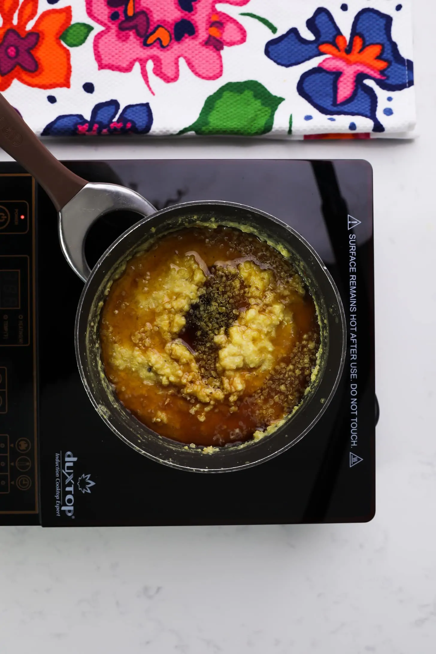 a saucepan with a mixture of yellow and brown liquid on a mobile stovetop.