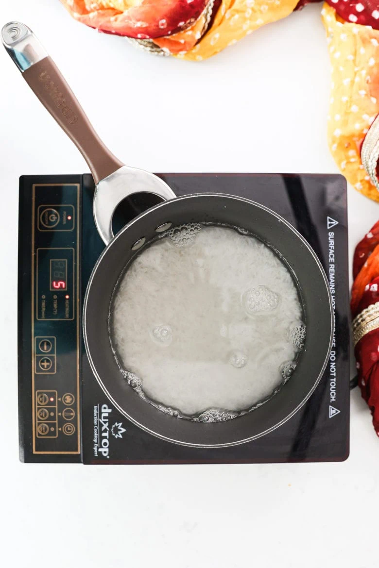 a saucepan filled with water and rice on a portable stove.