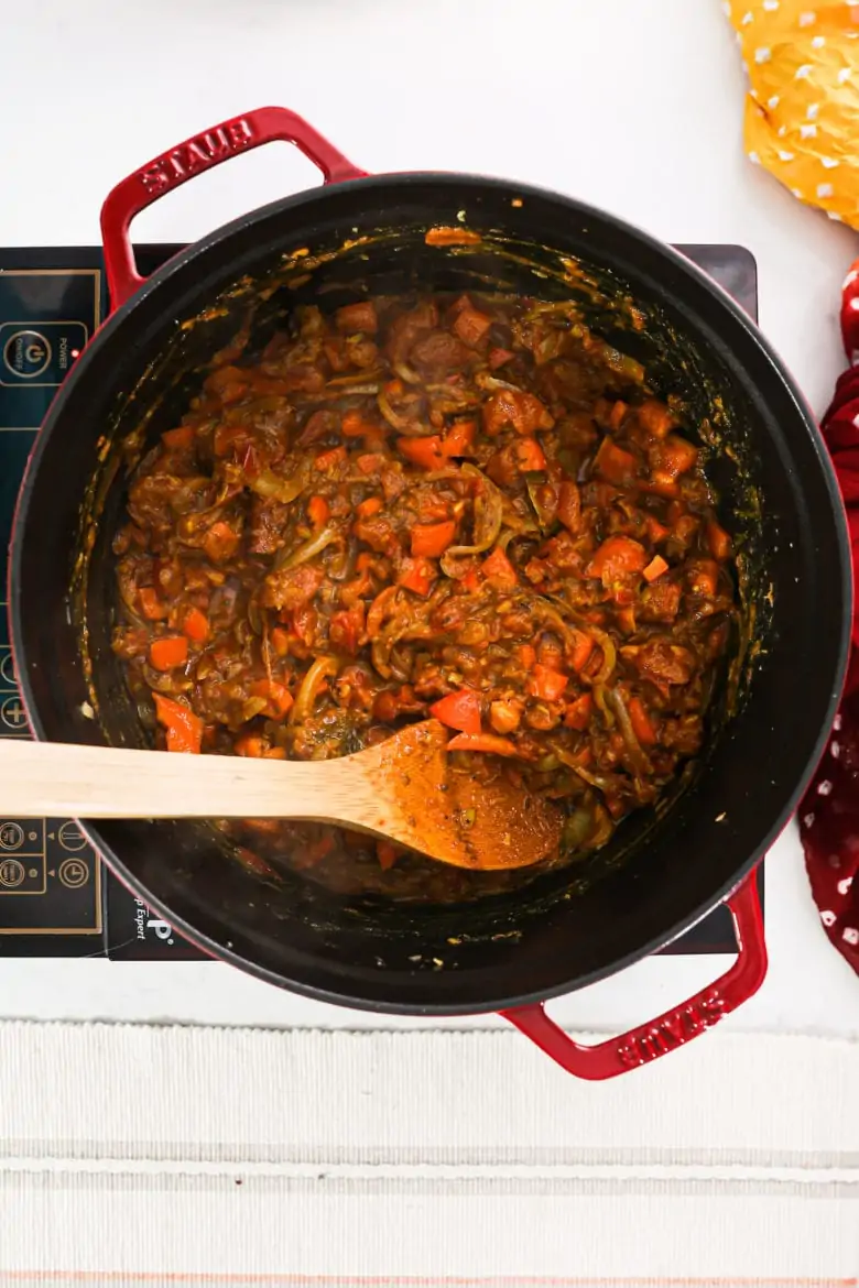 a large saucepan with a saucy mixture of tomatoes and onions.
