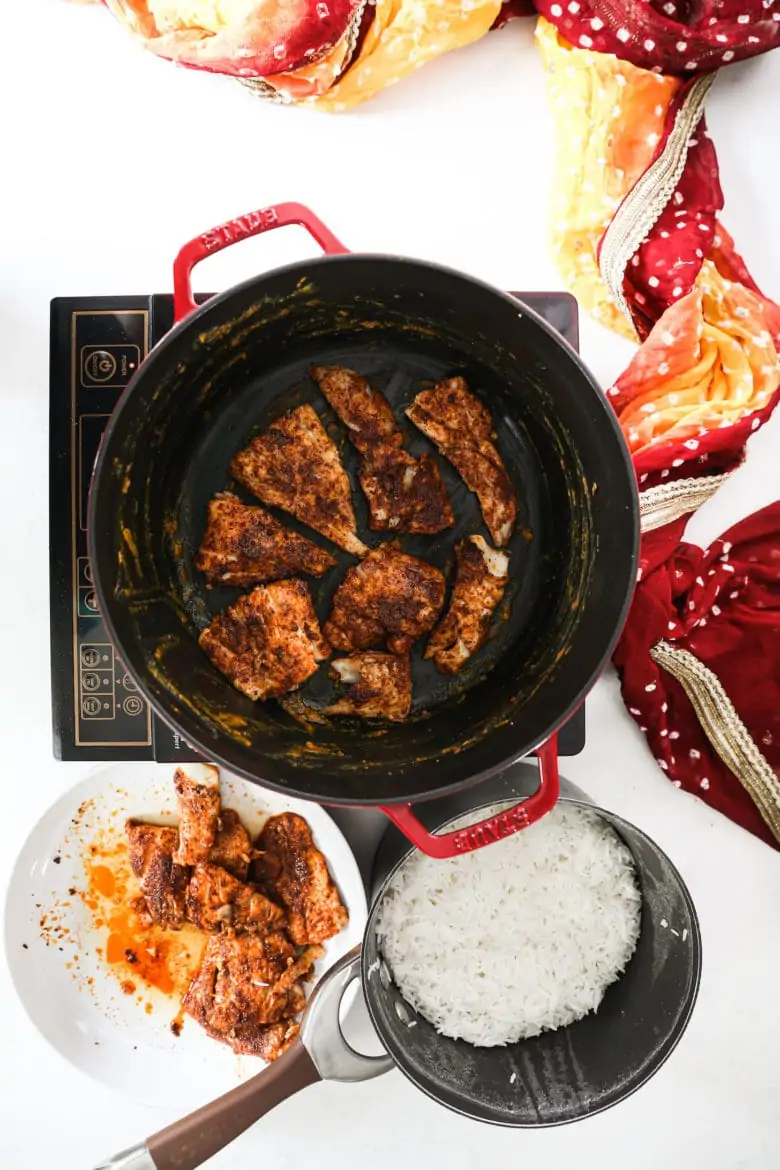 a large pot with fried fish as the first layer