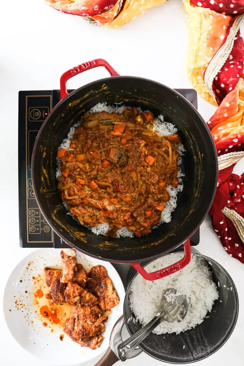 a large pot with a red tomato spicy sauce layered on top of rice.