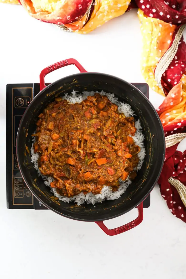 A large pot with a red tomato sauce layered on top of rice.