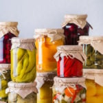 Preserved and fermented local food. Assortment of homemade jars with variety of pickled and marinated vegetables, fruit compote on a wooden table. Housekeeping, home economics, harvest preservation