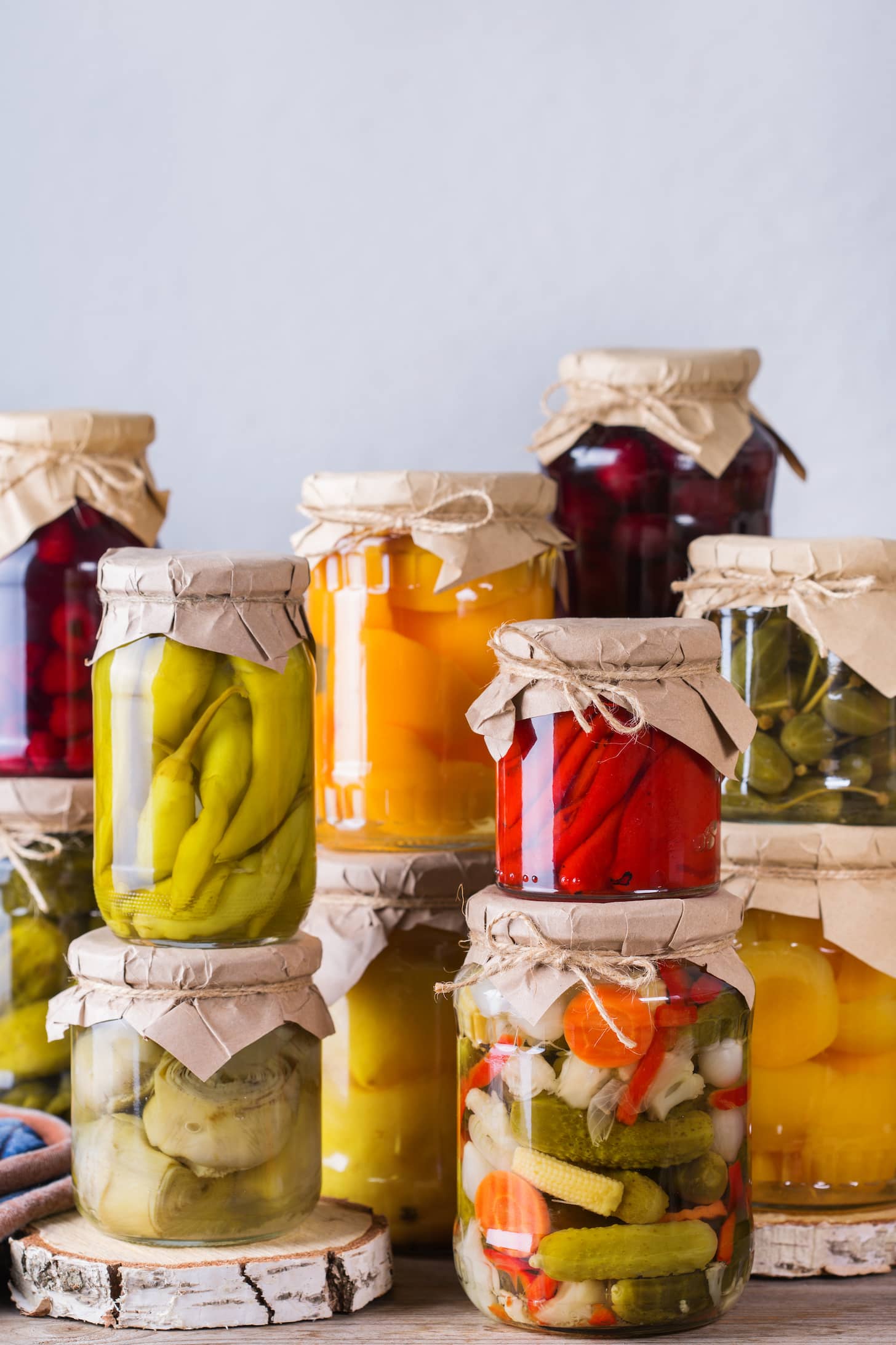 Preserved and fermented local food. Assortment of homemade jars with variety of pickled and marinated vegetables, fruit compote on a wooden table. Housekeeping, home economics, harvest preservation