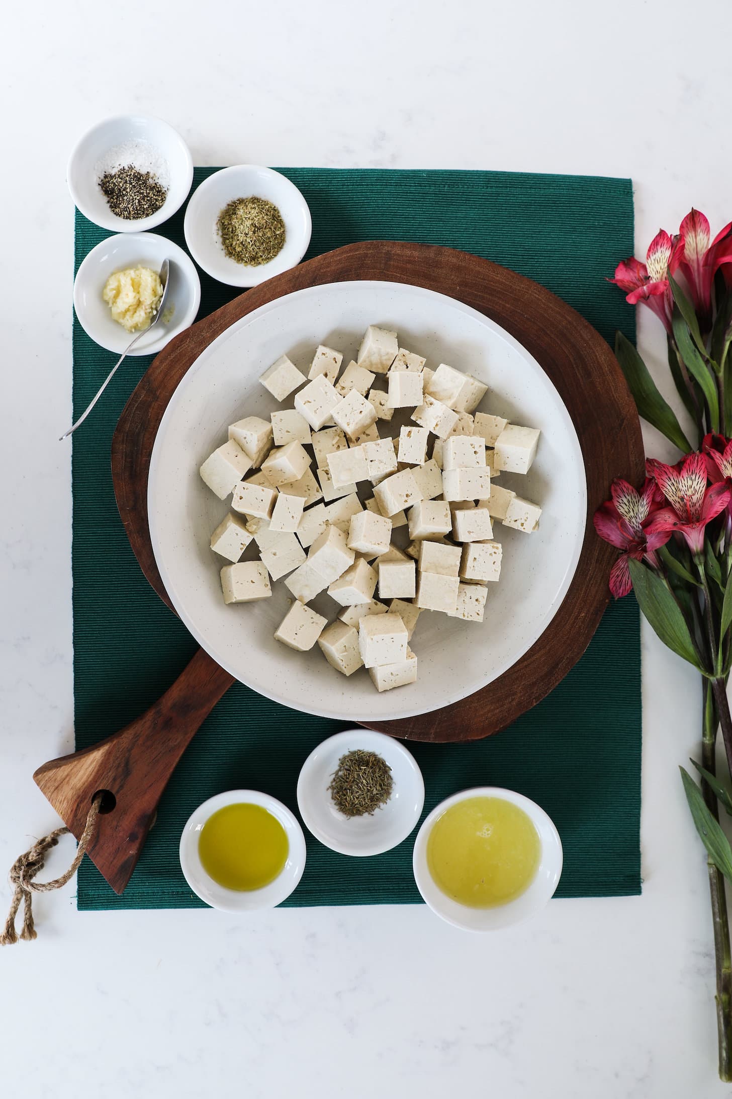 an array of ingredients including tofu cubes, oil, dried herbs, seasoning and juice.