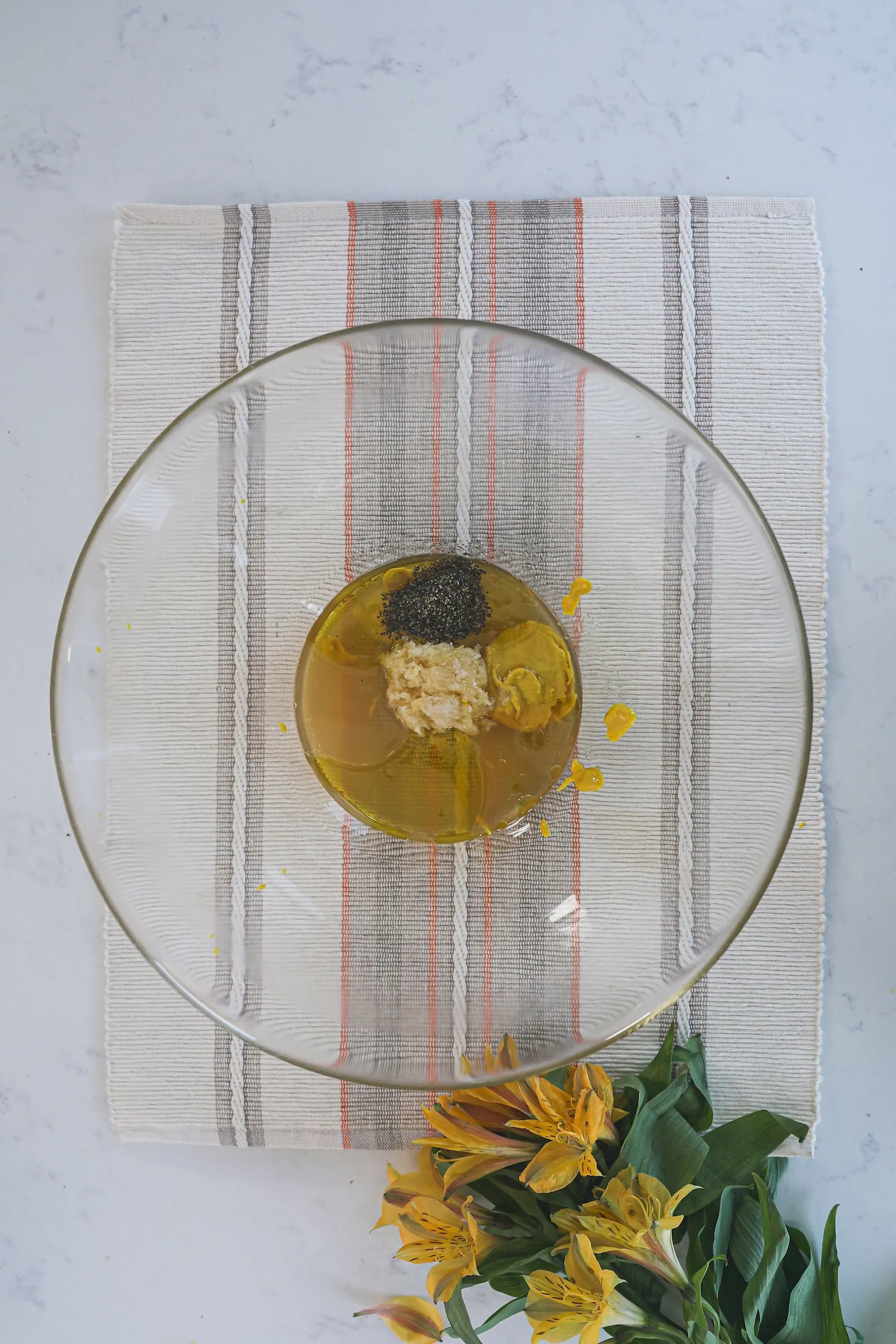 a large bowl with oil, chopped garlic, mustard and spices.