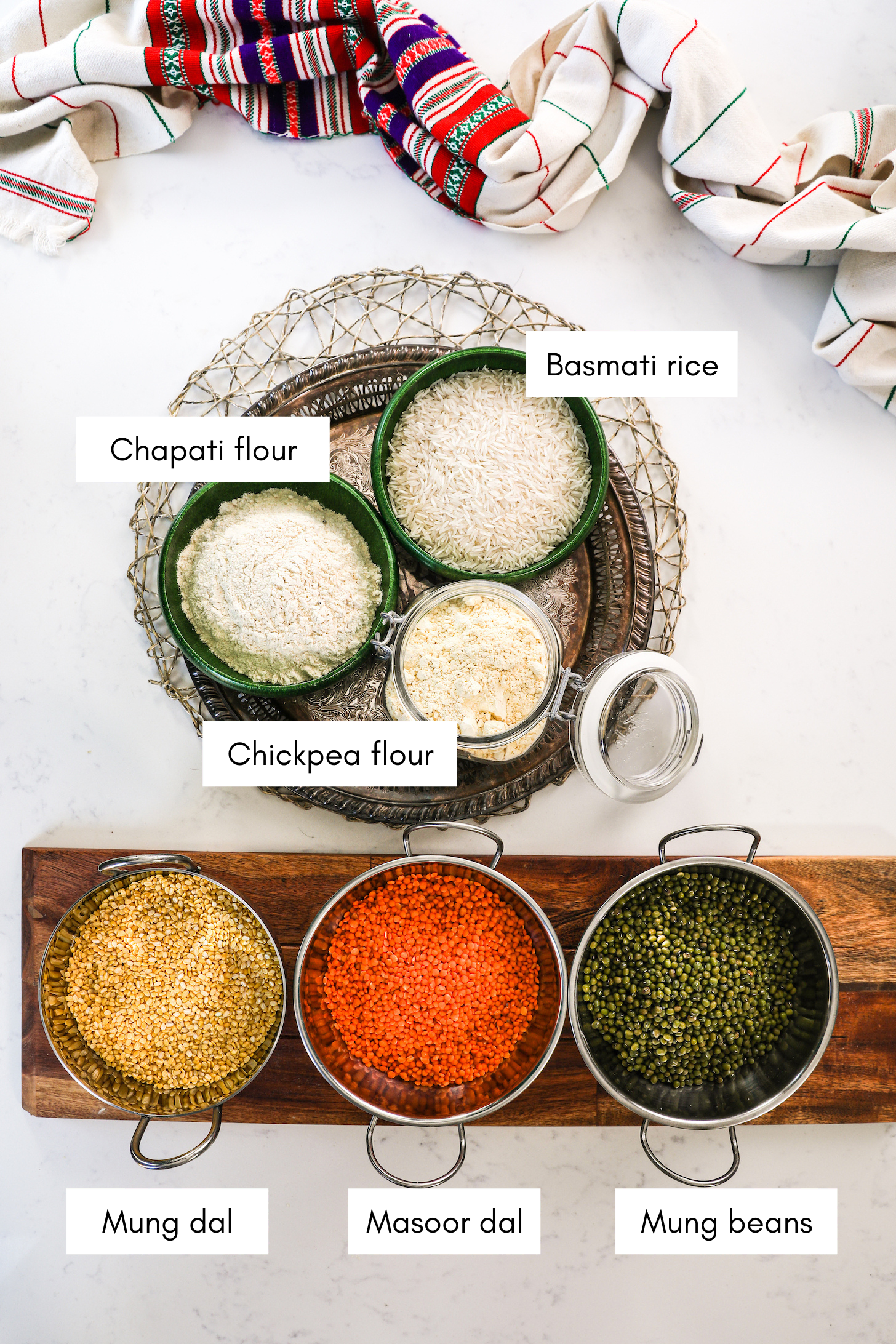 steel bowls of three types of lentils alongside dry goods including rice and flours.