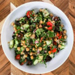 flatlay image of a bowl of salad made with chickpeas, avocados, cucumbers and herbs.