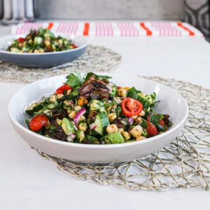 close up image of a bowl of salad made of chickpeas, cucumbers, tomatoes and herbs.