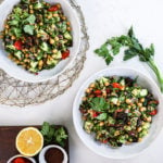 two bowls of salad made of chickpeas and cucumbers and herbs styled on top of a netted place mat.