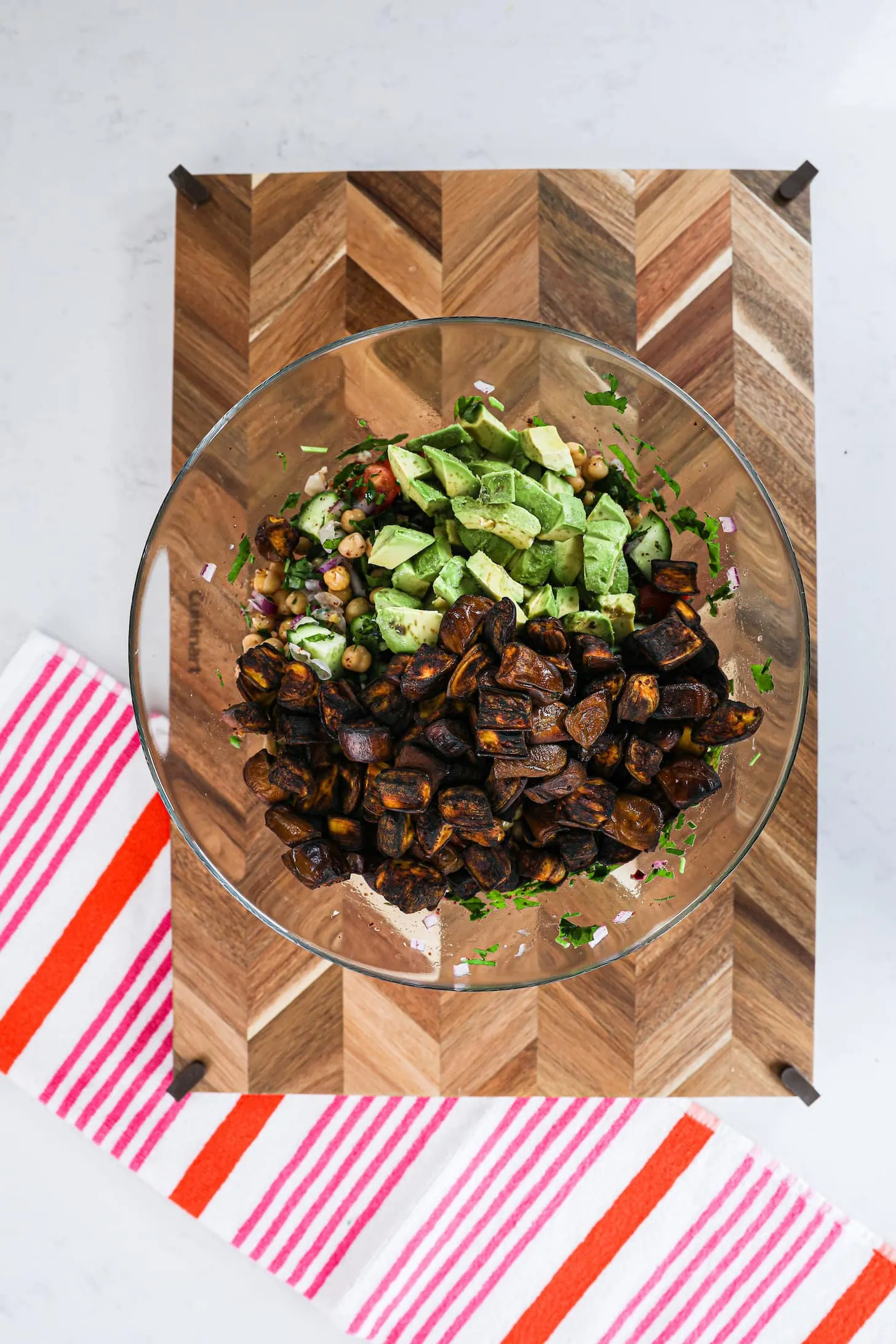 a bowl of brown cubes and avocado chunks on a wooden board.